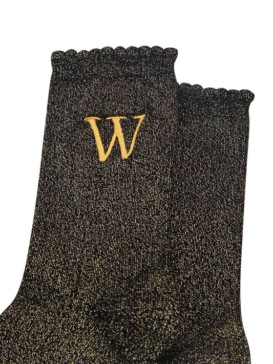 close up of the gold embroidered capital letter w on the ankle of the socks