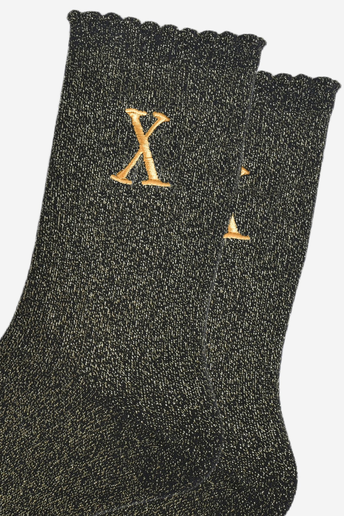 close up of the gold embroidered capital letter x on the ankle of the socks