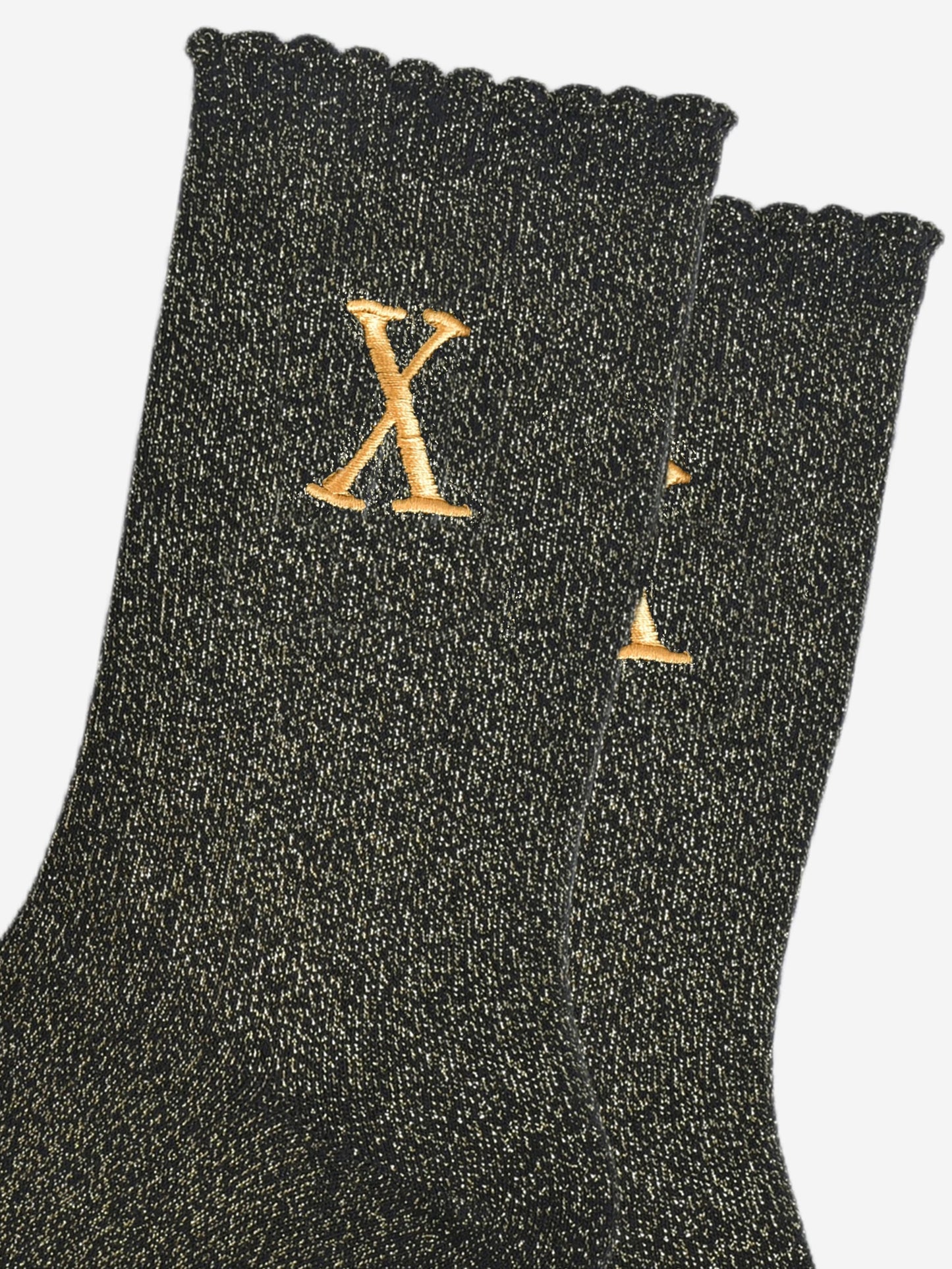 close up of the gold embroidered capital letter x on the ankle of the socks