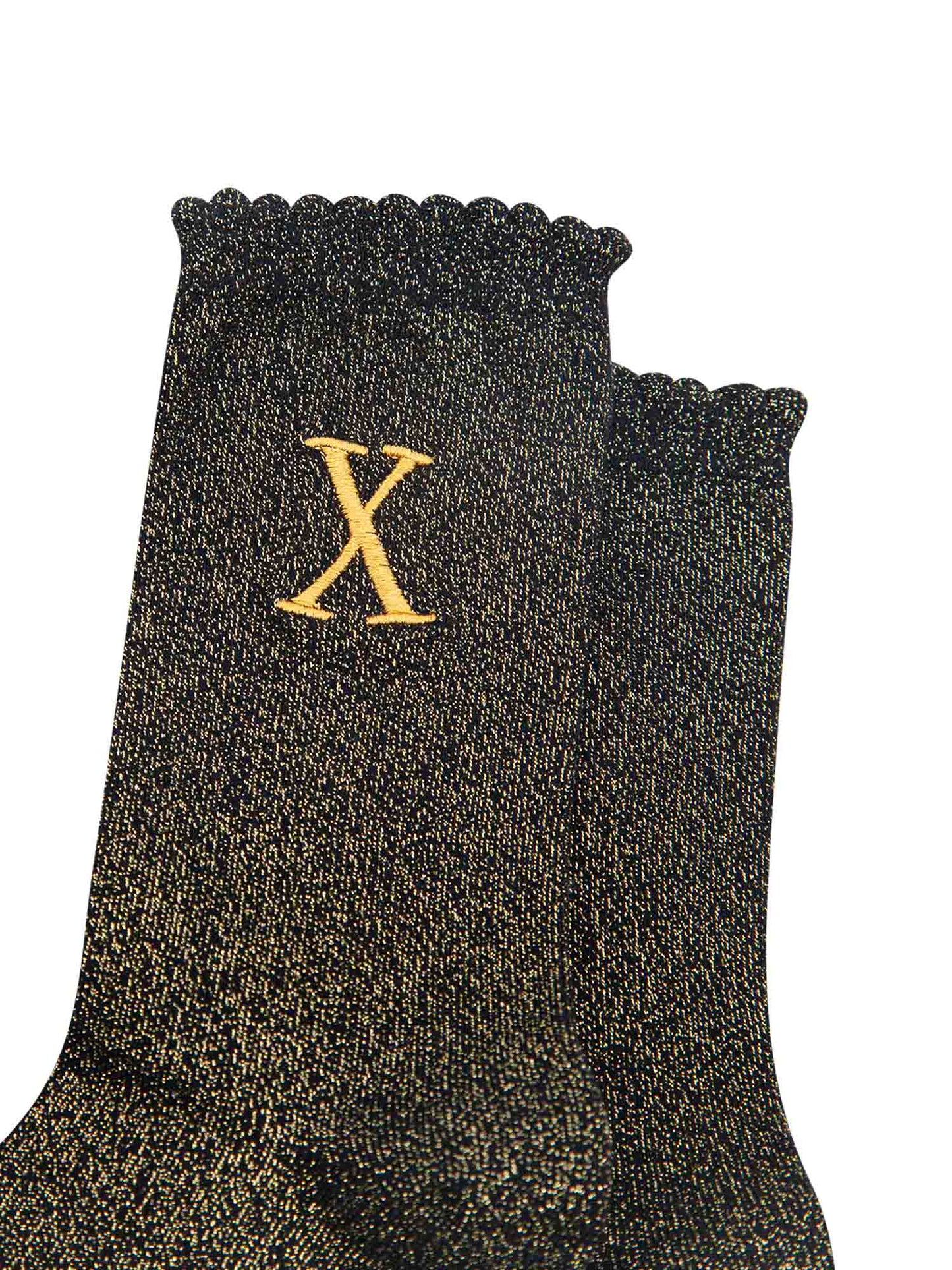 close up of the gold embroidered capital letter x on the ankle of the socks