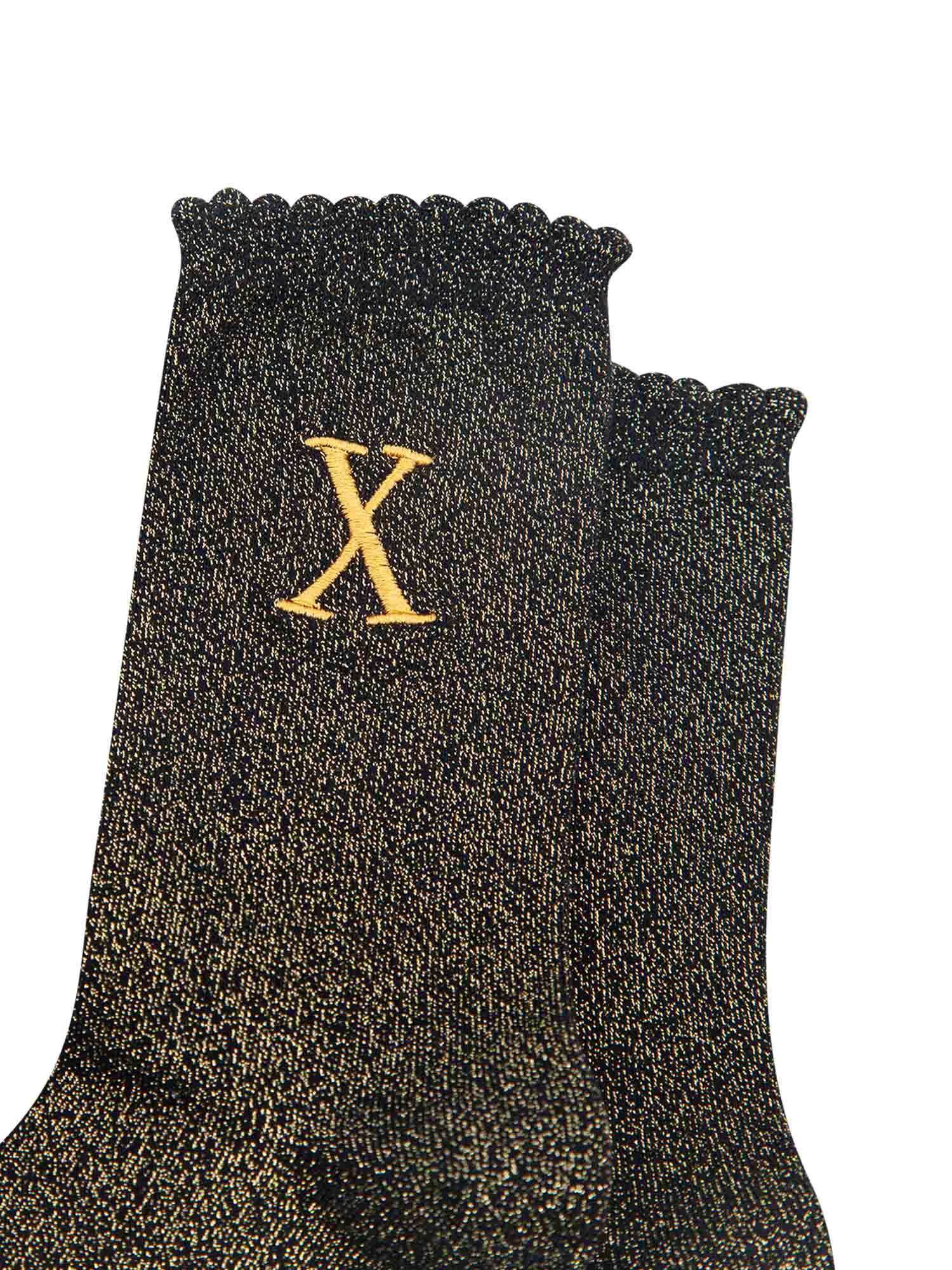 close up of the gold embroidered capital letter x on the ankle of the socks