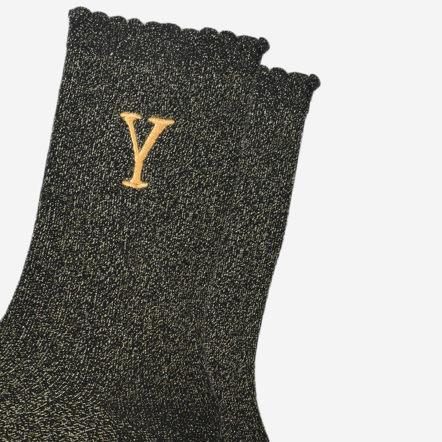 close up of the gold embroidered capital letter y on the ankle of the socks