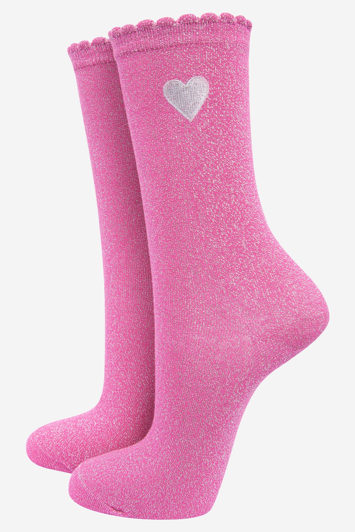 pink glitter socks with a silver embroidered heart motif on the ankle, the socks have an all over silver glitter shimmer and scalloped cuffs