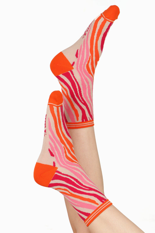 Women's feet posed in the air wearing sock talk bamboo socks in a pink and orange zebra print with orange contrasting toe and heel detail