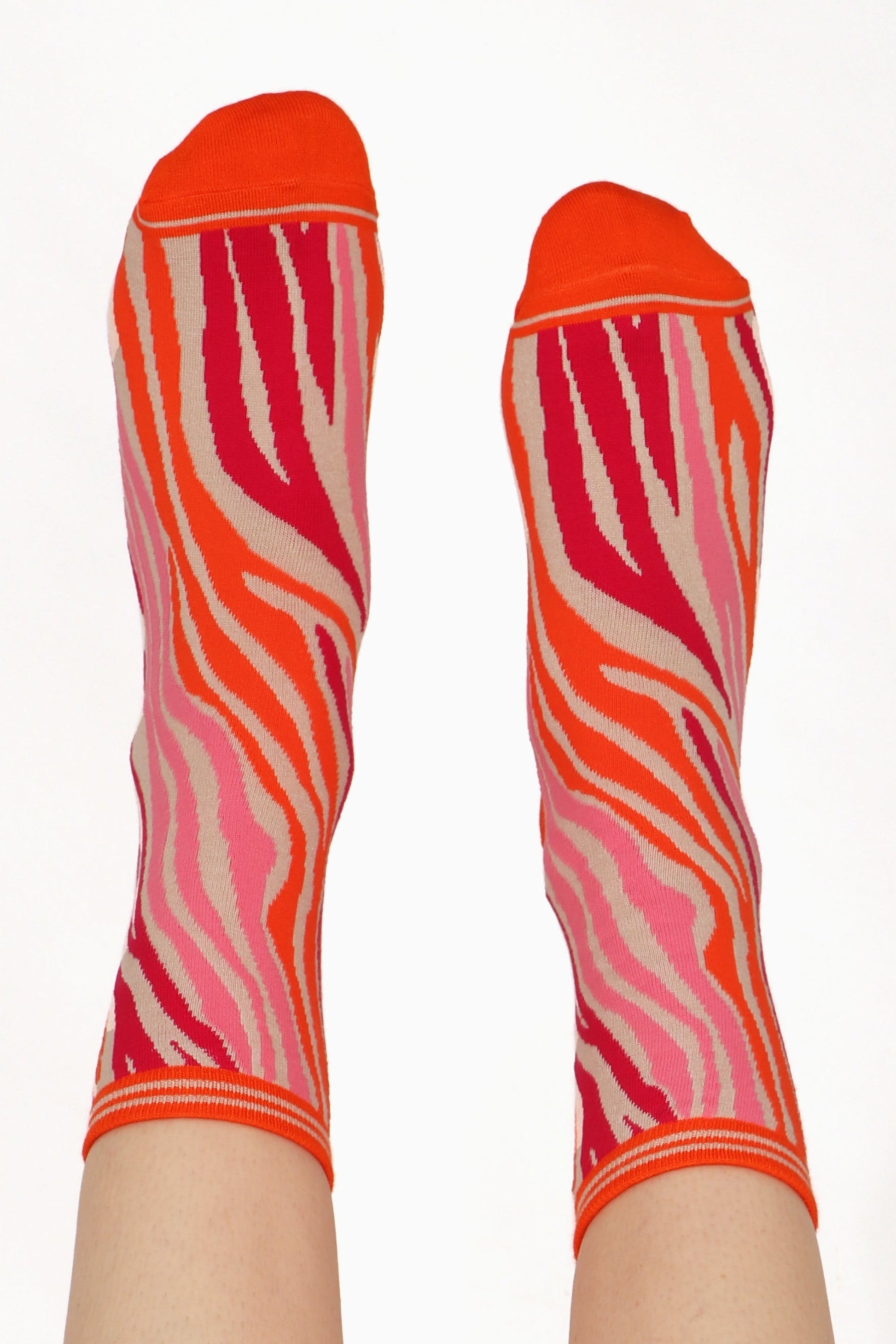 Women's feet posed straight in the air wearing zebra print bamoo socks in pink and orange tones
