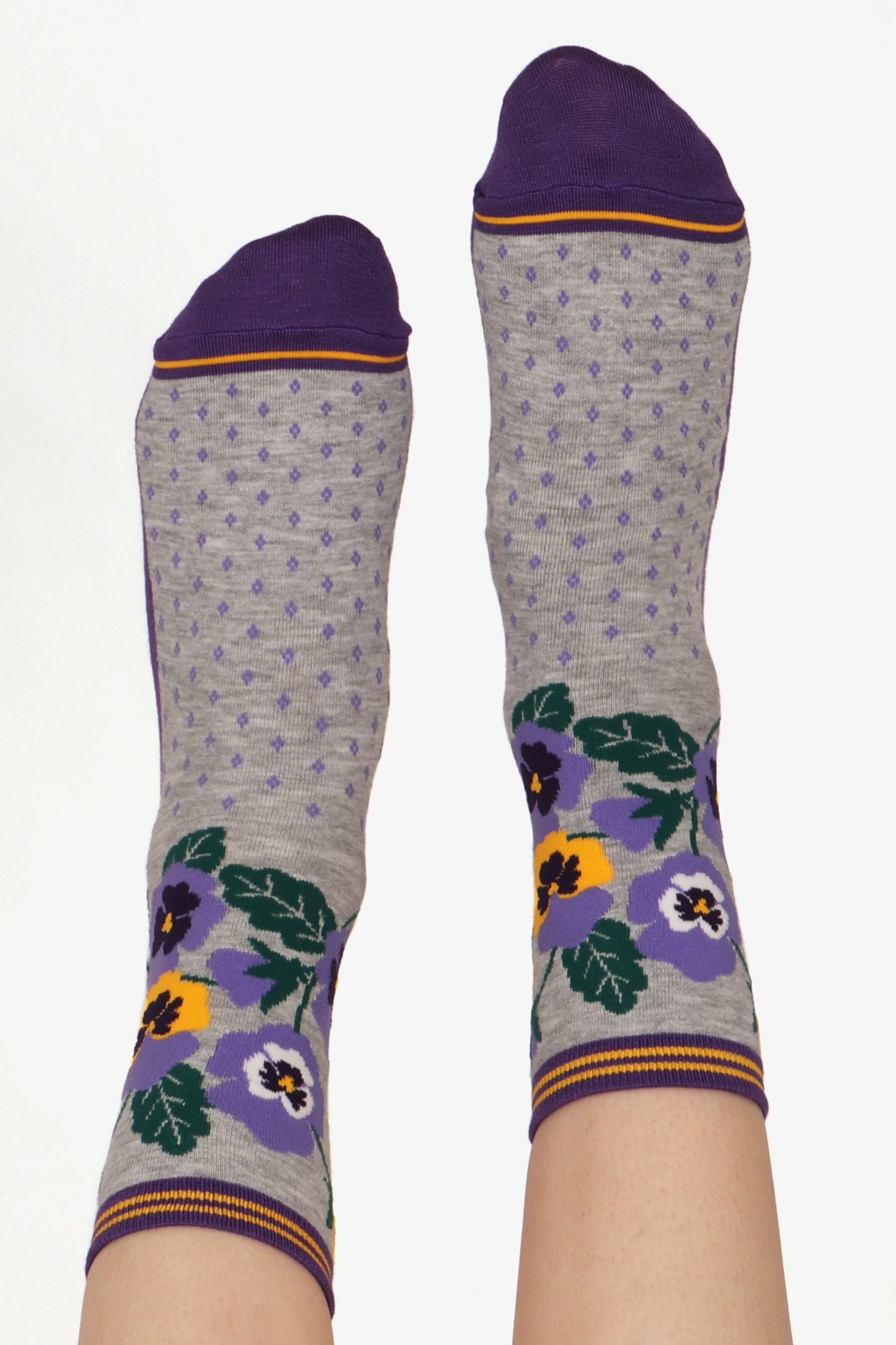 Ladies feet posed straight in the air. Image shows floral pansy print on bamboo fibre socks. Purple toe detail highlighted