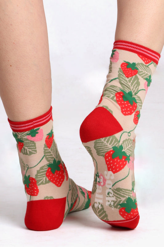 ladies feet facing away from camera wearing strawberry print bamboo socks. Image highlights contrasting heel and sock talk logo on sole of sock