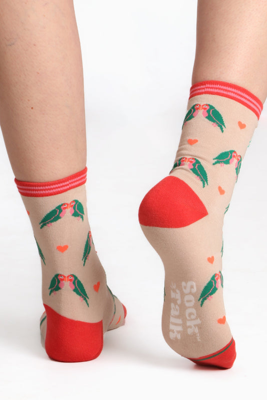 Ladies feet in sock talk bamboo socks. Walking away from the camera image with sock talk logo on sole highlighted. Contrasting toe and heel detail can be seen. Socks are lovebird printed,