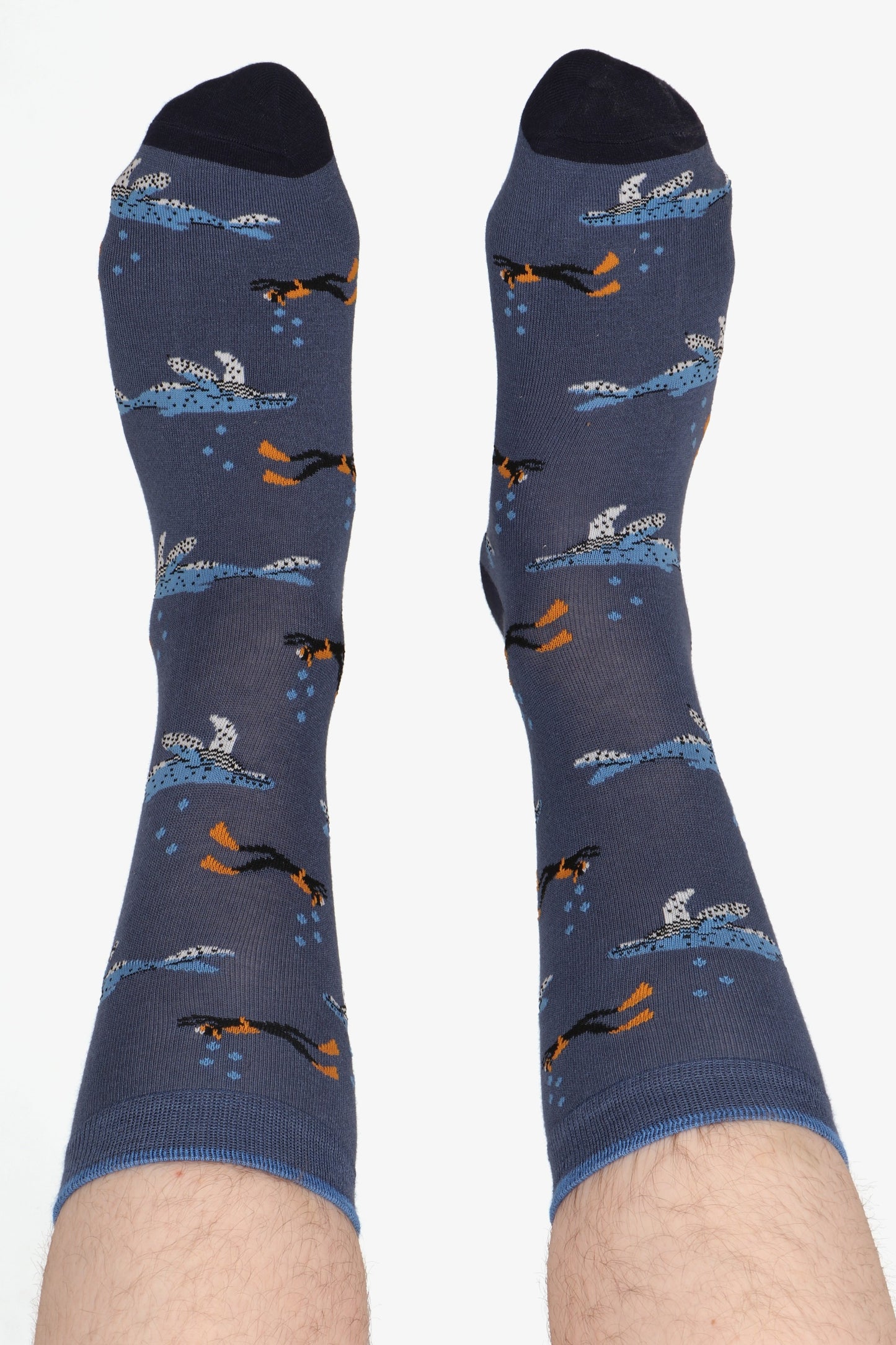 Men's feet wearing tropical fish print socks. Feet are in the air and highlight the contrasting toe detail