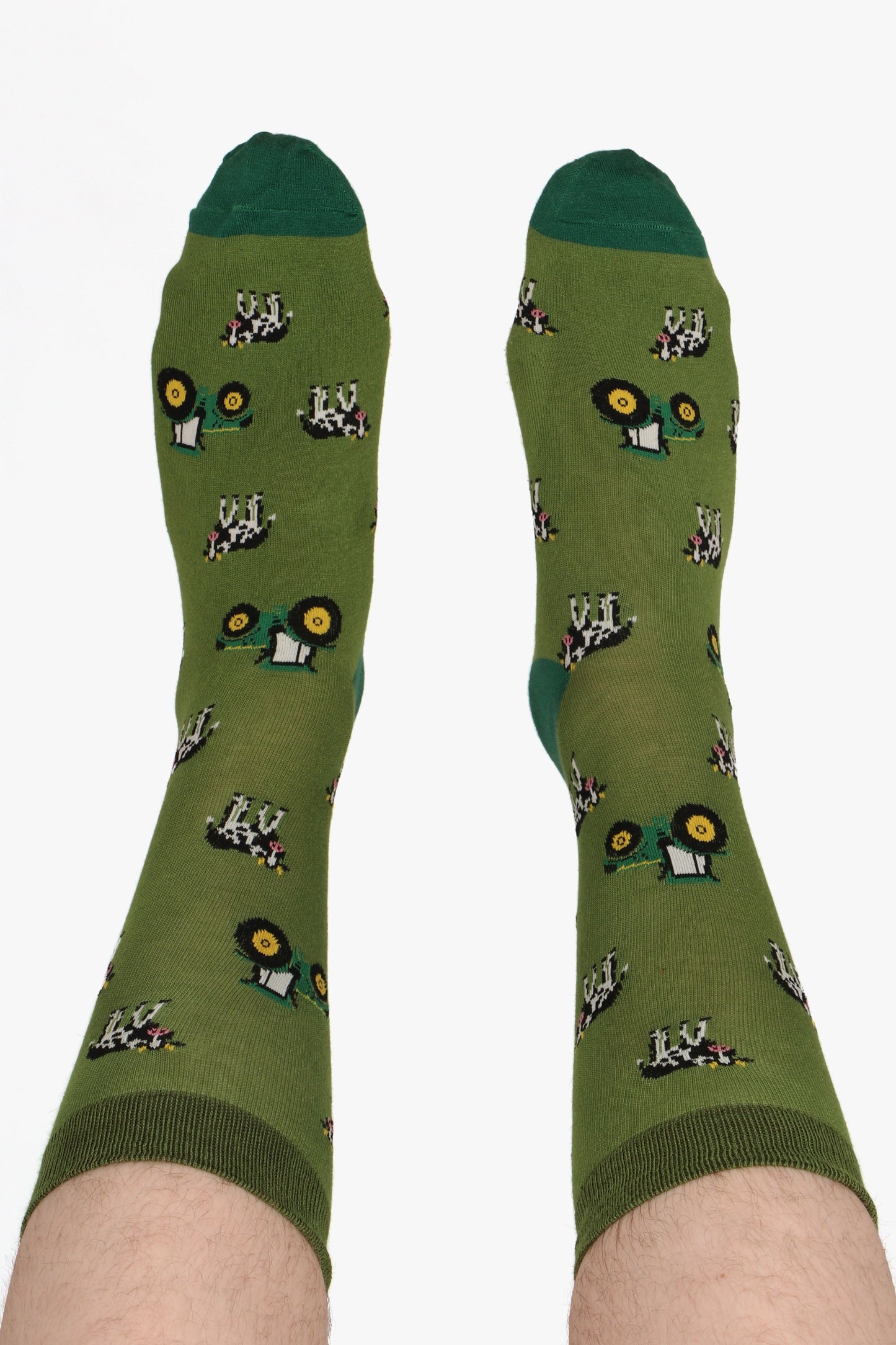Mne's bamboo socks in tractor and cow print. Socks are in green tones. Male models feet are in the air