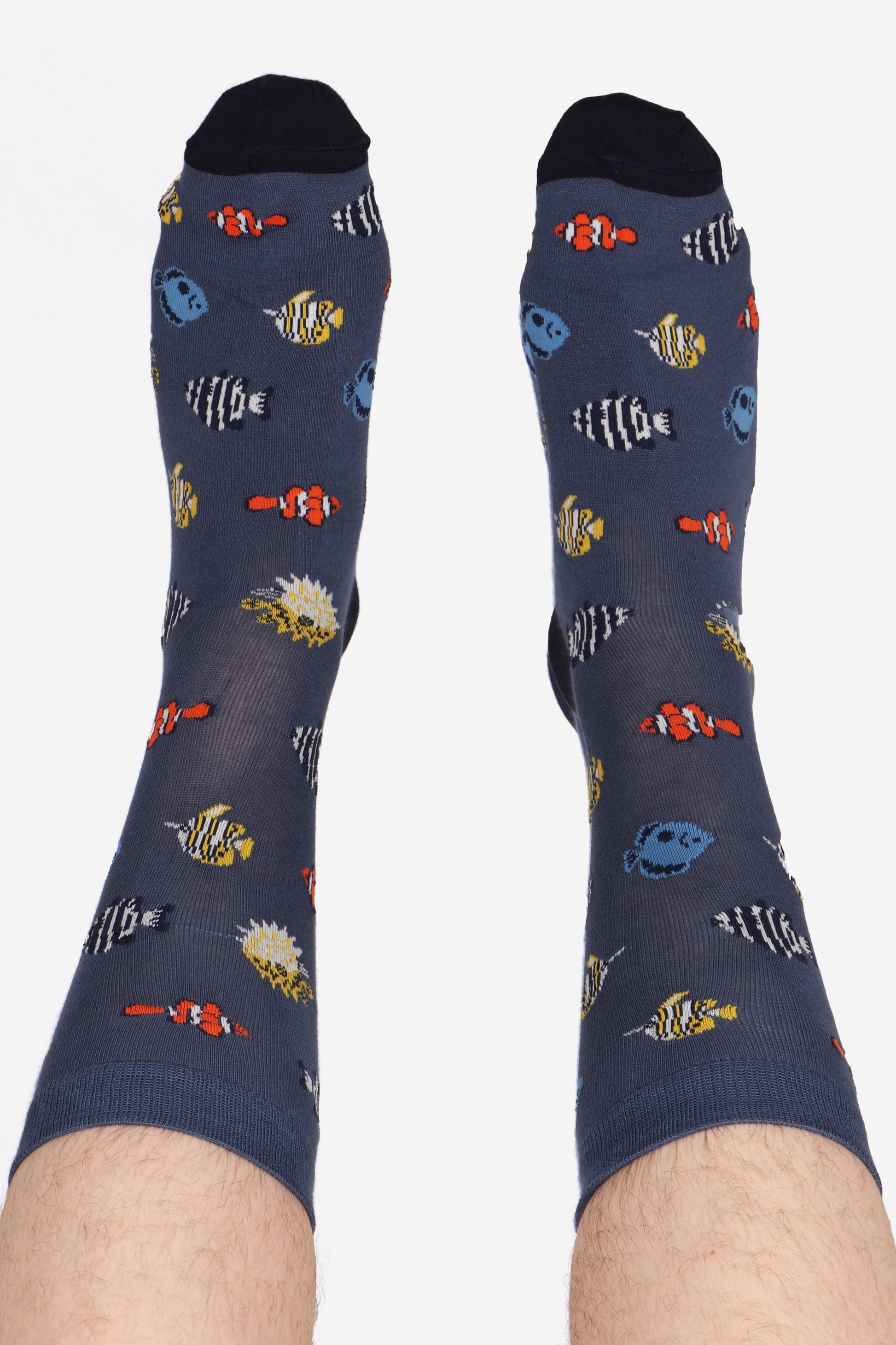 Men's tropical fish print bamboo socks in navy blue. Men's feet are in the air and show off contrasting blue toe detail