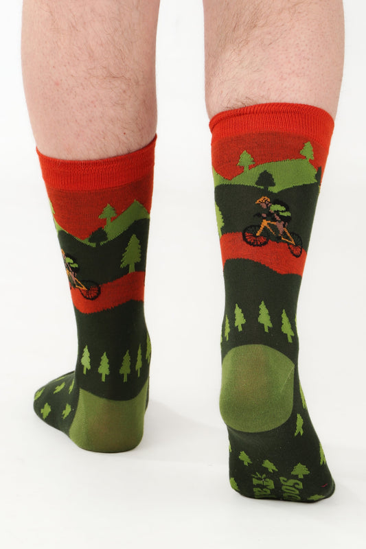 Male model feet walking away from camera to show sock talk logo on sole of bamboo sock. Sock is mountain bike themed