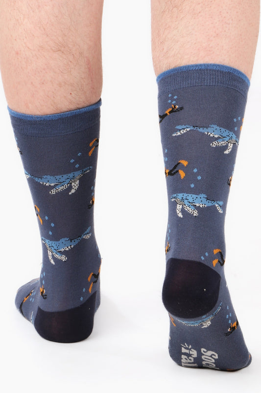 Men's feet walking away from camera wearing scuba diving themed bamboo socks in blue tones. Image highlights sock talk logo on sole of foot along with contasting heel detail