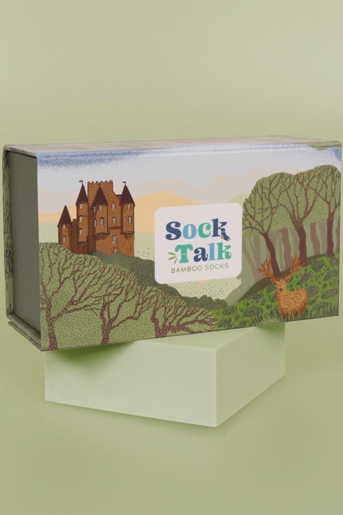 a sock gift box designed to look like a rural scottish highland scene with a castle, stag and woodlands