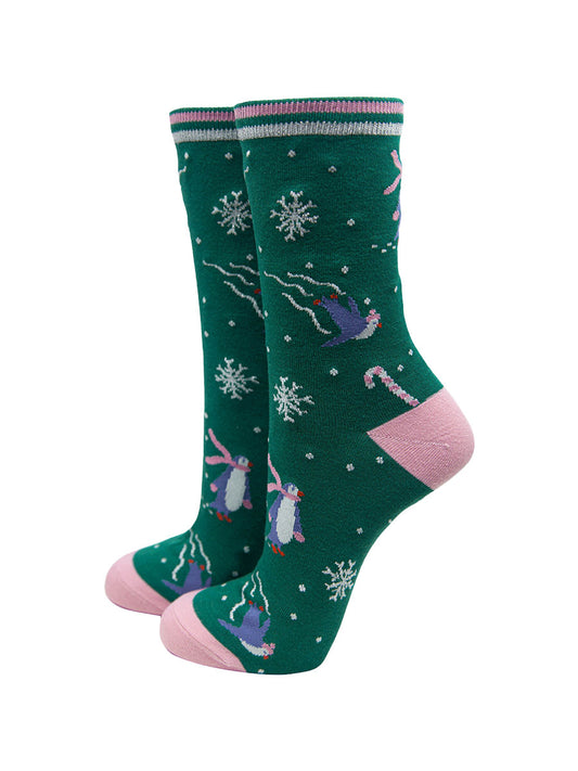 green socks with pink heel, toe and stiped cuff with a pattern of ice skating penguins, candy canes and snowflakes, with silver glitter accents