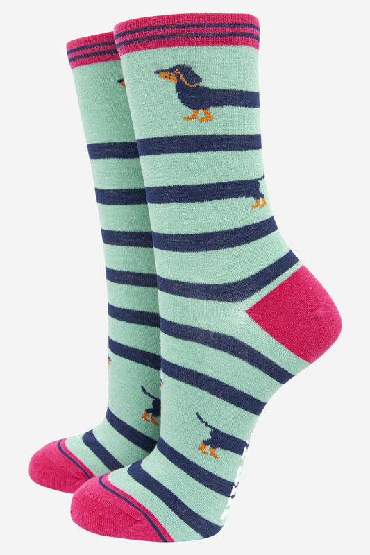 mint green ankle socks with pink heel, toe and cuff with a navy blue sausage dog winding itself around the sock giving the socks a striped appearance