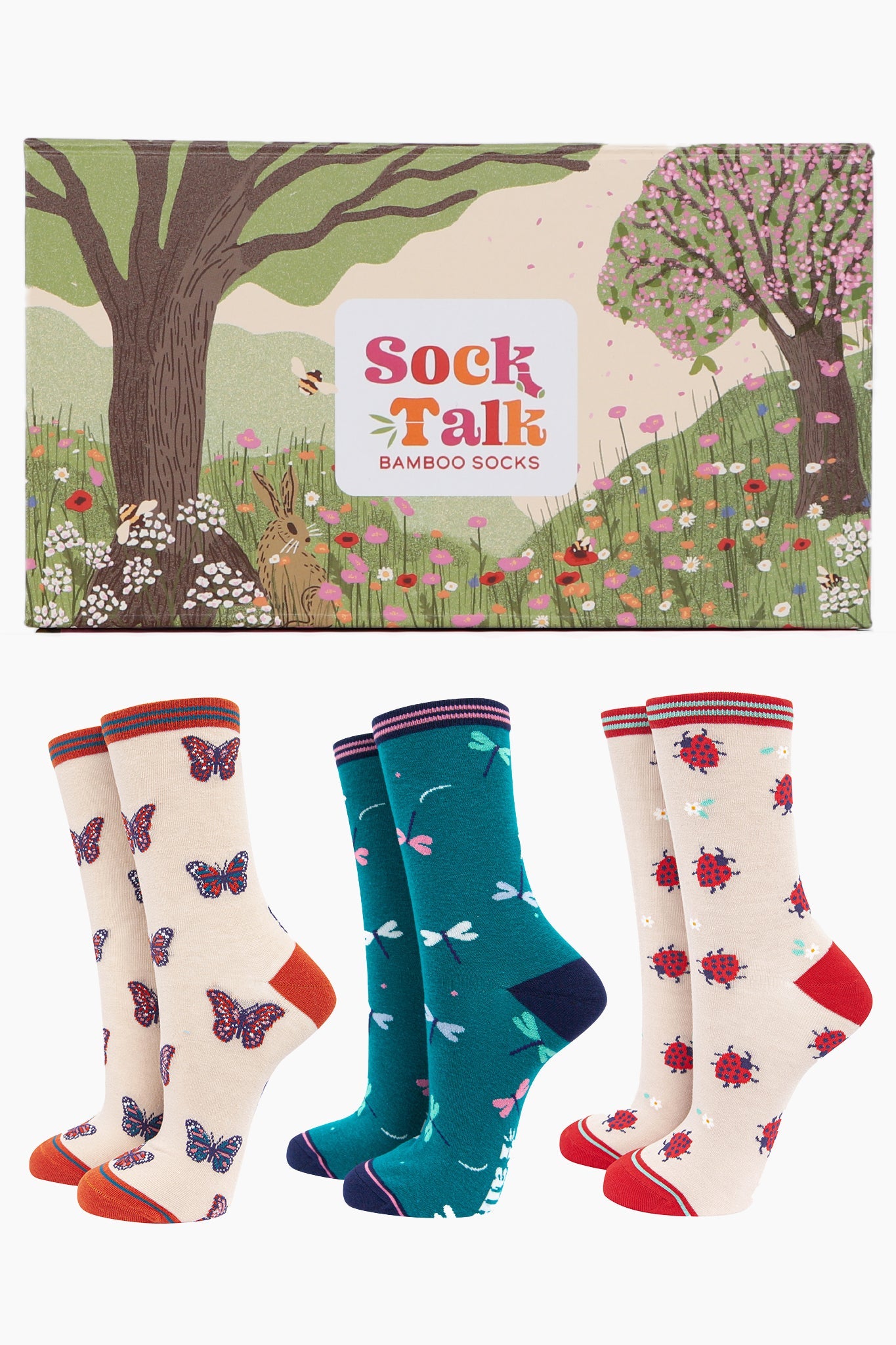 an artistically designed gift box with a summer meadow scene with wild flowers, trees and bees with three pairs of ladies bamboo socks. One pair of butterfly socks, one with ladybirds and one featuring dragonflies