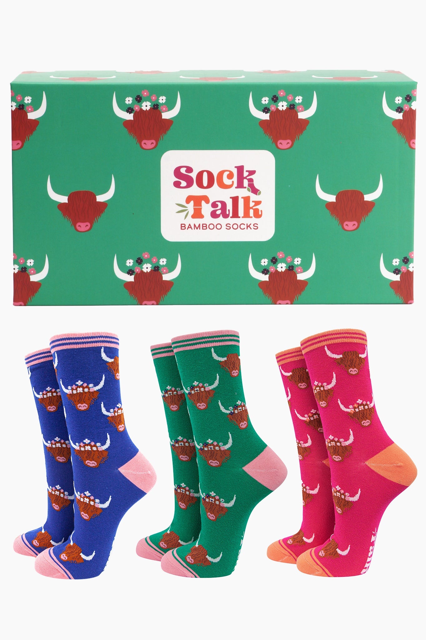 an artistically designed green gift box with an all over pattern of highland cows wearing floral crowns, there are three colourful pairs of highland cow pattern socks in this gift set, one pink, one green and one blue pair of bamboo ankle socks