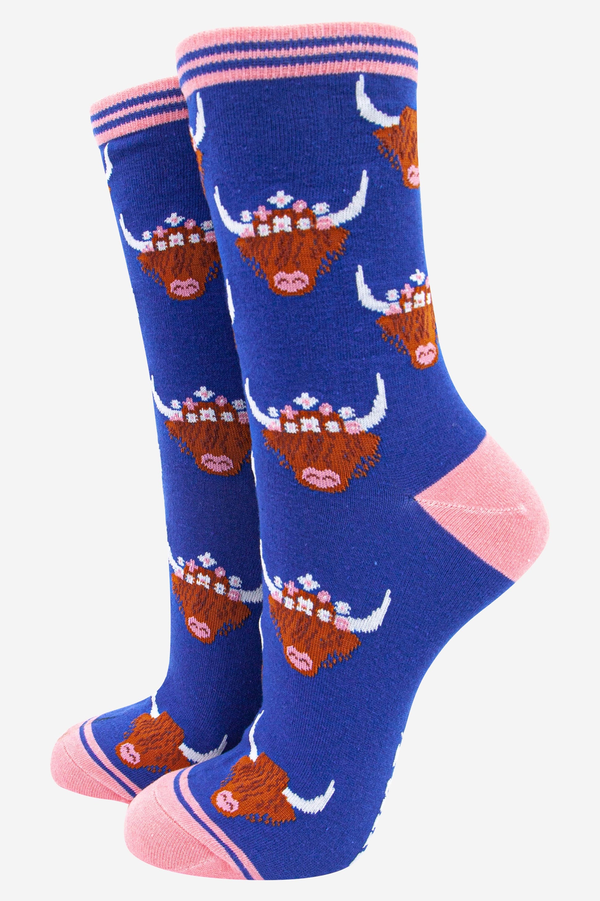 blue bamboo socks with pink heel, toe and trim with an all over pattern of brown highland cow faces with horns the cows are wearing floral wreaths as crowns