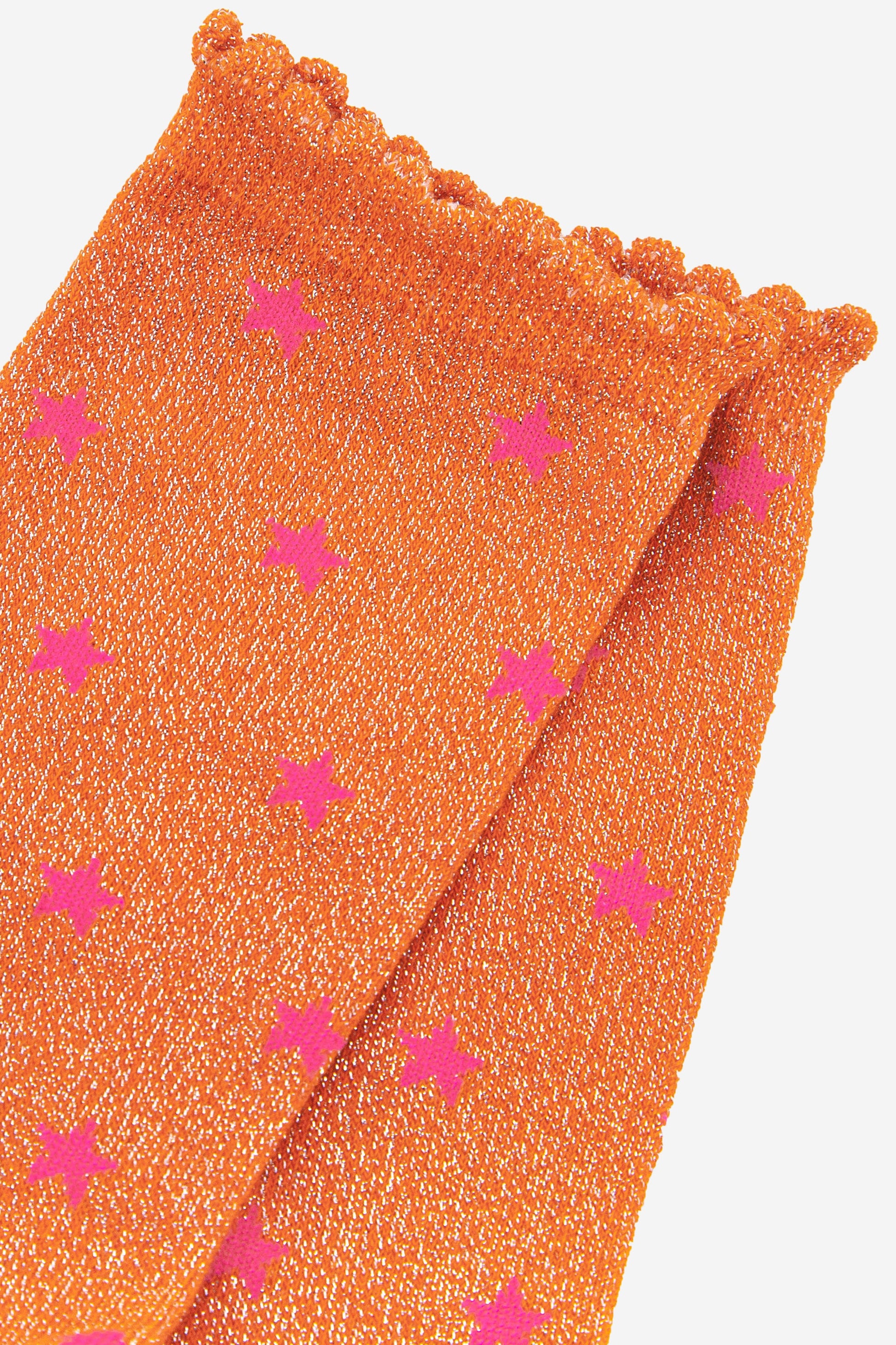 close up of the pink star pattern on the orange glitter socks